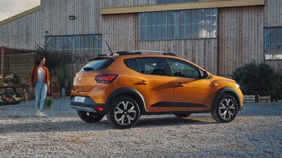 side view of a dacia sandero stepway and a woman standing behind it