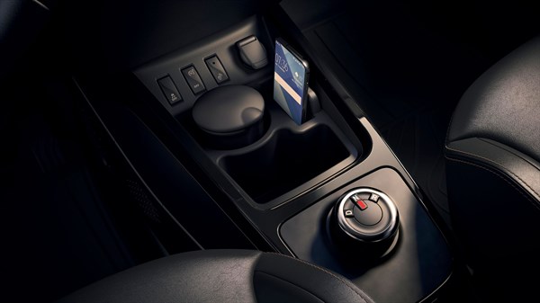 Center console of a car with control buttons, cup holder, and smartphone slot