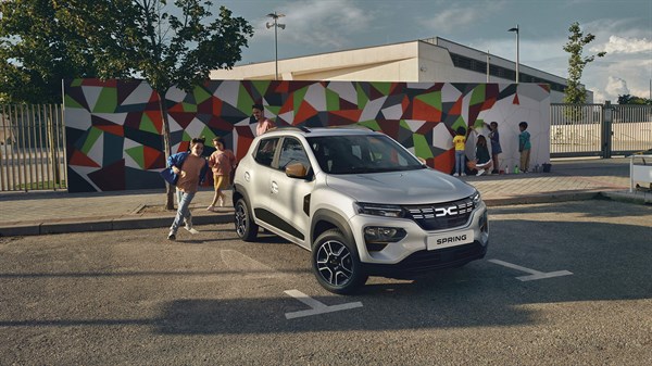 dacia spring parked outside a school and the children are running to it