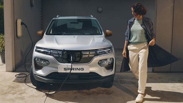 a woman is charging the dacia spring