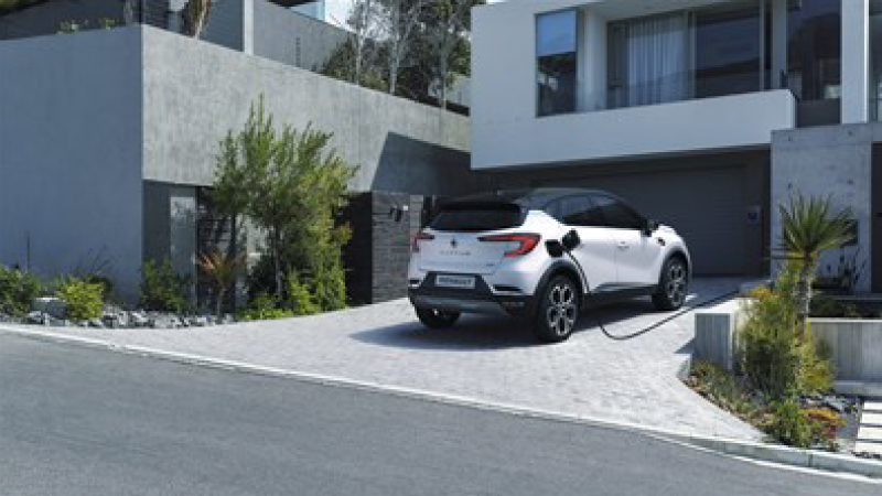 a white captur is outside from a home garage and charging