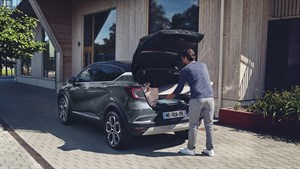 A man is placing some bags in the truck of the car