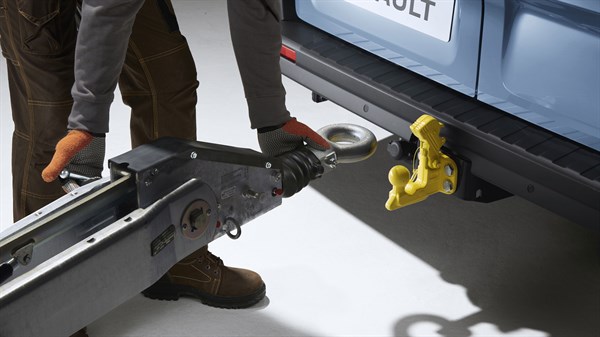 a blue renault new trafic where someone is attaching a tow hitch to the rear of a vehicle