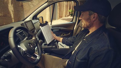 a man is sitting inside the renault new trafic and reading some documents