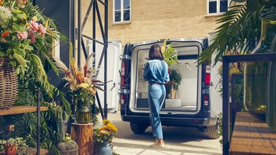 a woman is putting plants in a renault new trafic